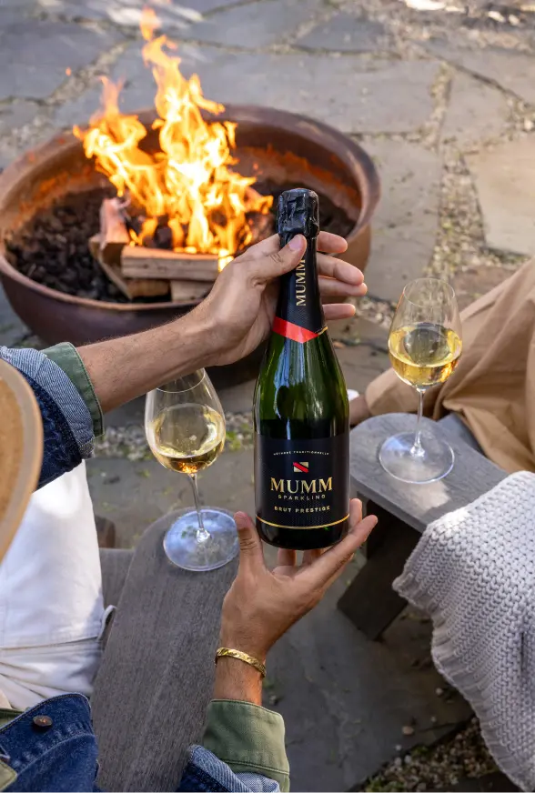 Friends checking out a bottle of Mumm Sparkling Brut Prestige